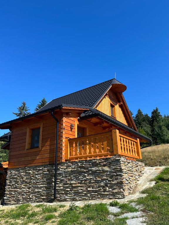 eine Blockhütte mit einer Veranda und einem Dach in der Unterkunft Malebný chalet Benešky in Velké Karlovice