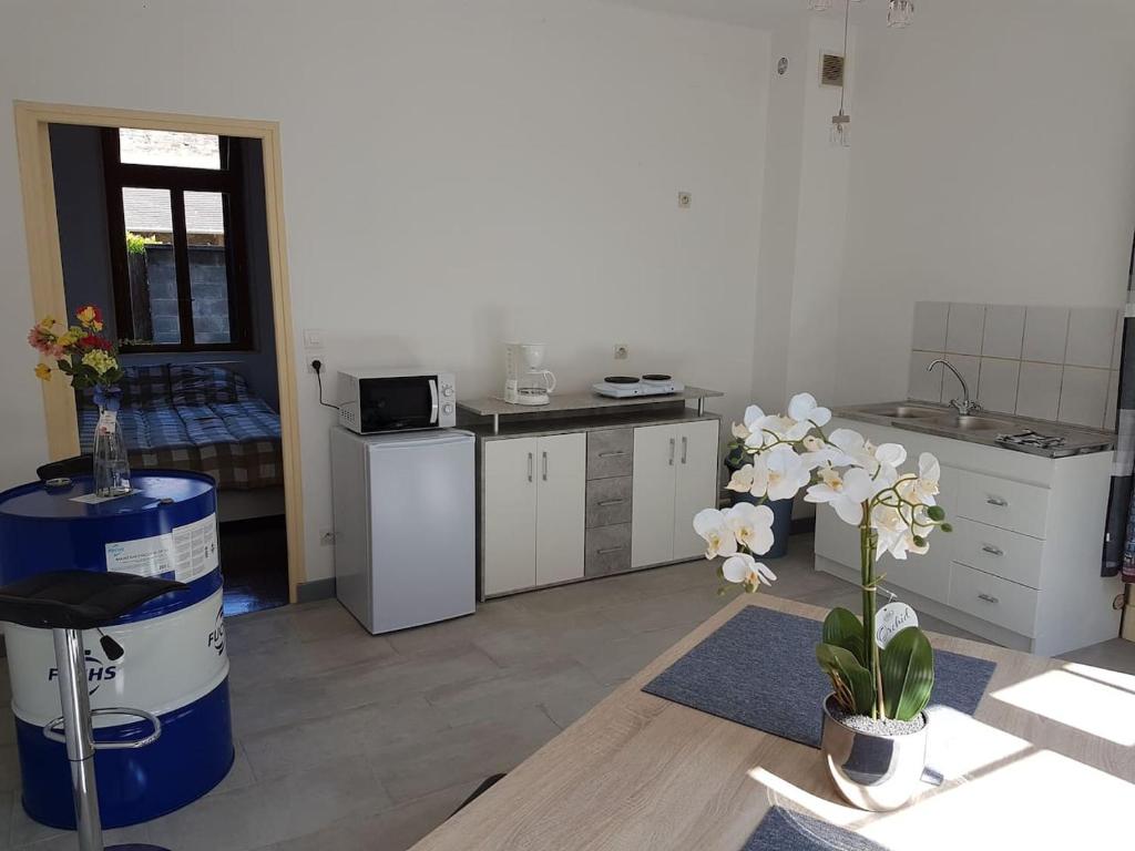 a kitchen with white cabinets and a table with flowers at F1 centre ville in Bohain-en-Vermandois