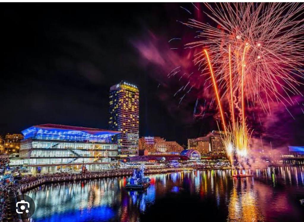 a fireworks display over a river with a city at Darling Harbour in Sydney