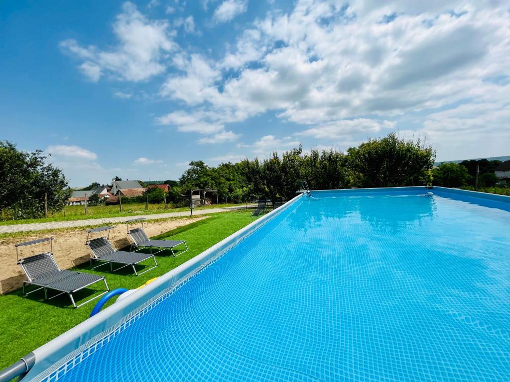een groot zwembad met 2 ligstoelen ernaast bij Berky Kúria - Stylish cottage in the Hills of Tolna for 16people in Nagykónyi