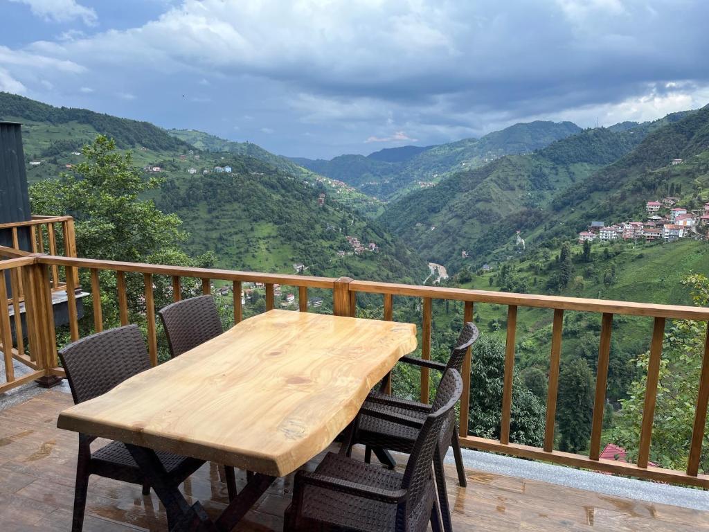 una mesa de madera y sillas en un balcón con montañas en Masarona 2 nolu Dağ evi, en Çamlıhemşin