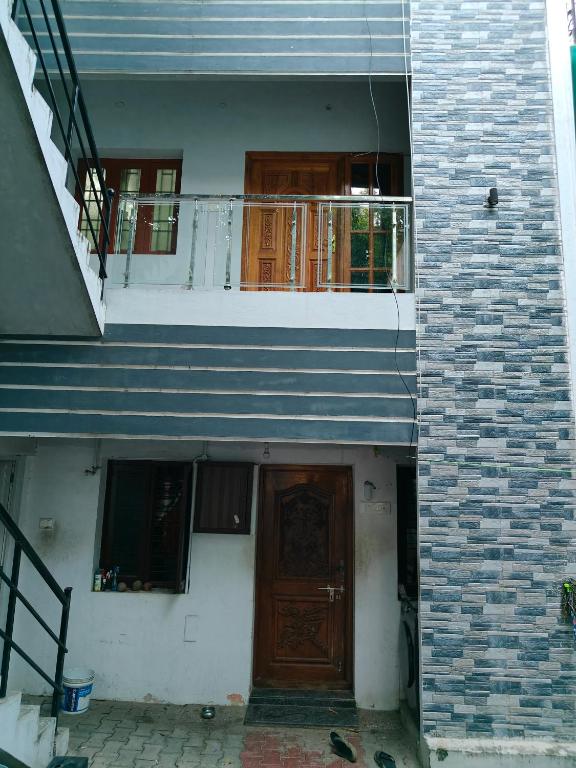 uma casa com uma porta de madeira e uma varanda em Fiona Homestay em Chennai