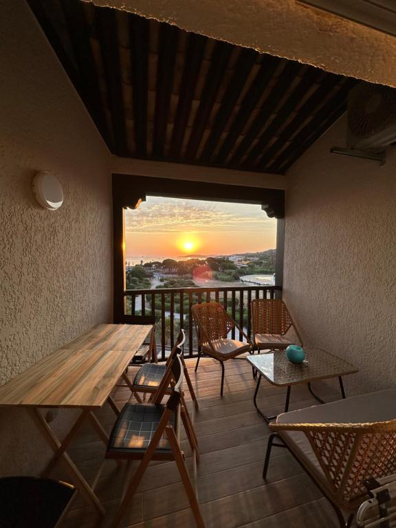 d'un balcon avec une table et des chaises et un coucher de soleil. dans l'établissement Appartement cosy climatisé à 100m des plages, à Gassin