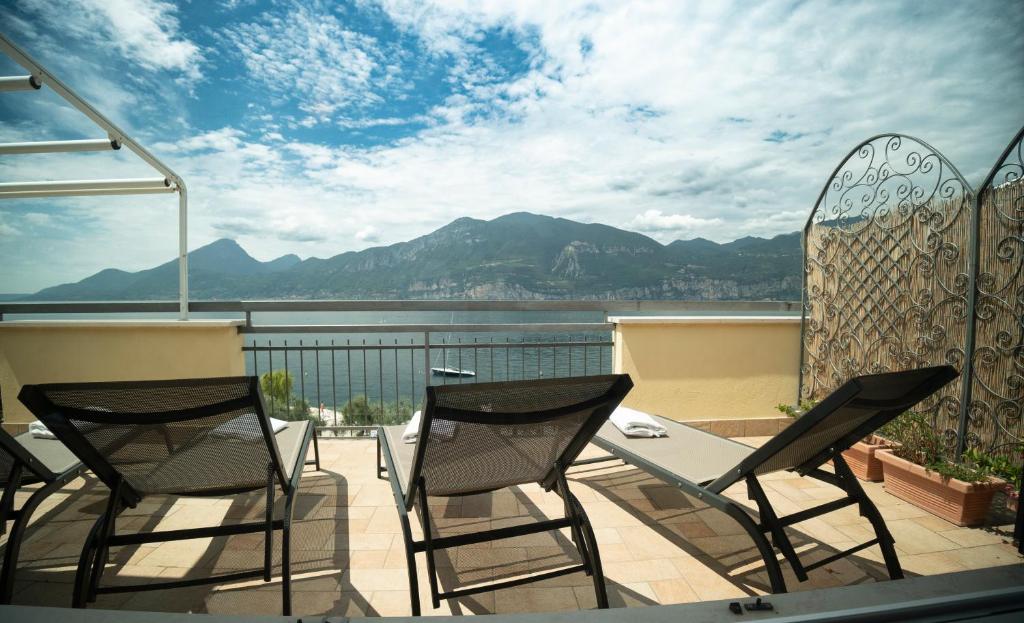 einen Balkon mit Stühlen, einem Tisch und Blick auf das Wasser in der Unterkunft Attico Masse Lake view in Brenzone sul Garda