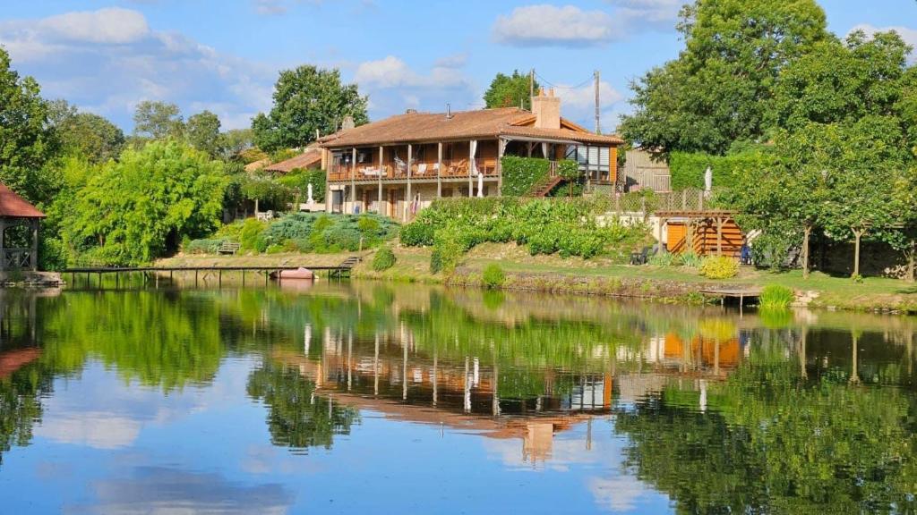 a house sitting on the side of a river at Lake Noble in Saint-Germain-lʼAiguiller