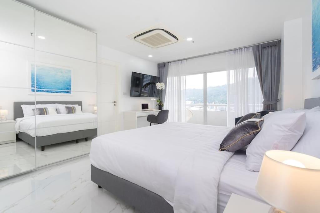 a white bedroom with a large bed and a window at Patong Tower Brand New 1-Bedroom , Near Beach in Patong Beach
