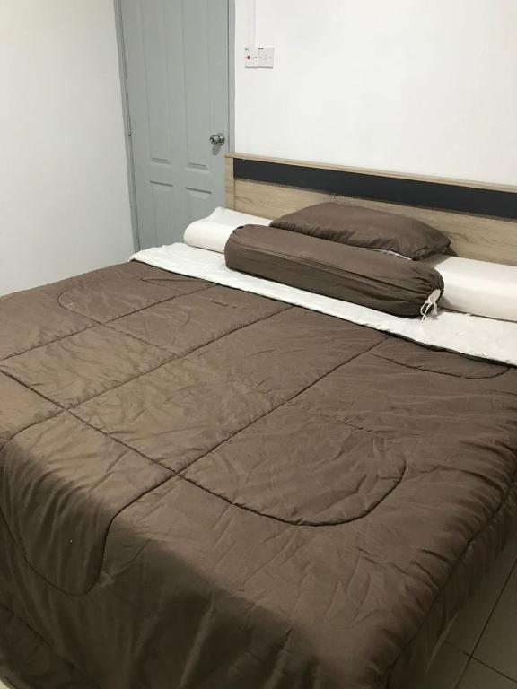 Una cama con una manta marrón encima. en M1 Budget Comfortable Central en Kuching