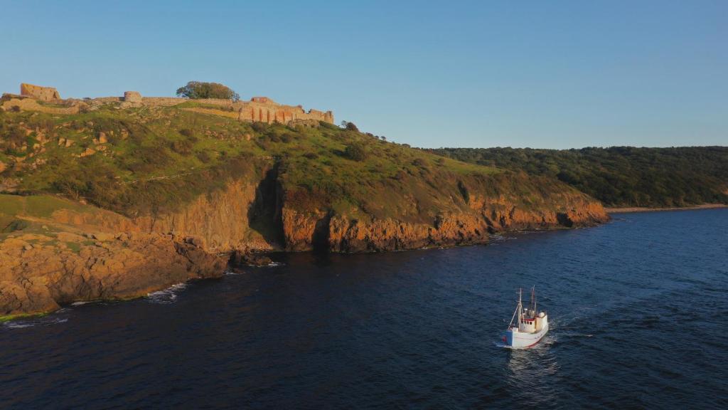 a small boat in the water next to a cliff at Unique Boat Accomodation - Fjælstavn - Bornholm in Hasle