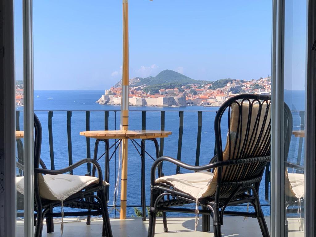 un balcón con 2 sillas, una mesa y el océano en Beach house Sveti Jakov, en Dubrovnik