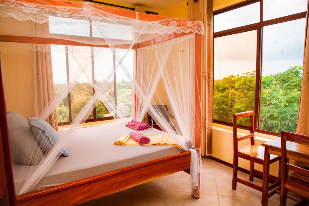 1 dormitorio con cama con dosel y ventana en Mikoko Beach & Cottages, en Bagamoyo