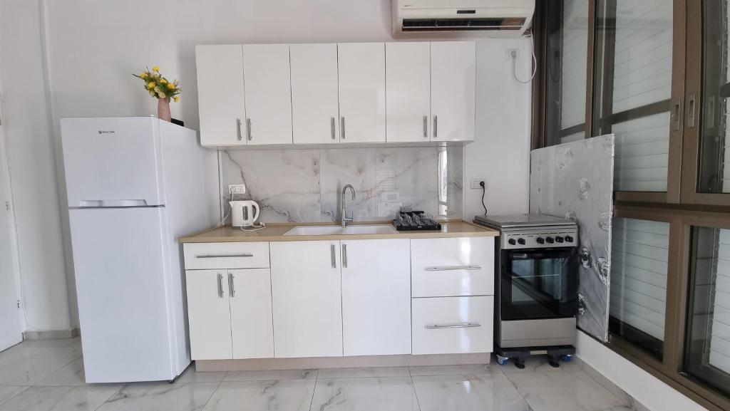 een keuken met witte kasten, een wastafel en een koelkast bij New Stylish Apartment with Balcony Close to Tel Aviv in Bene Beraq