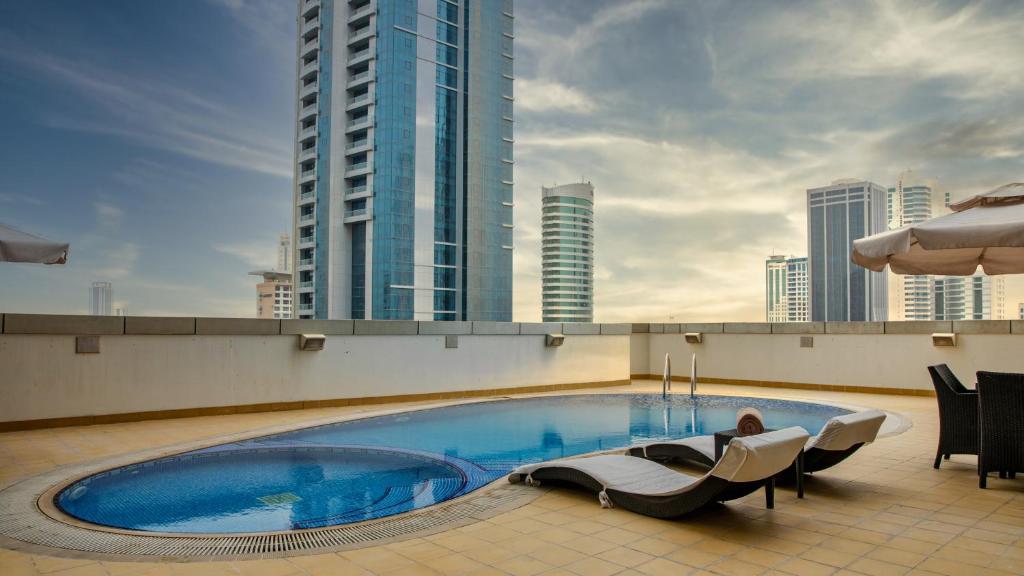 a person laying on the roof of a building with a pool at S Hotel Bahrain in Manama