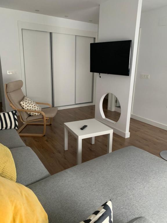 - un salon avec une télévision et un canapé dans l'établissement Coqueto apartamento en Gijon, à Gijón