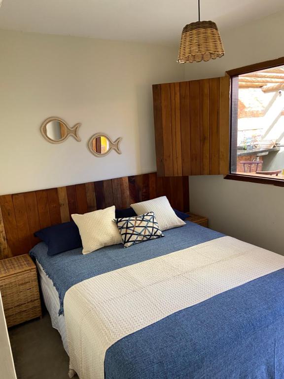 1 dormitorio con cama con sábanas azules y ventana en Casa Prainha, en Praia do Frances