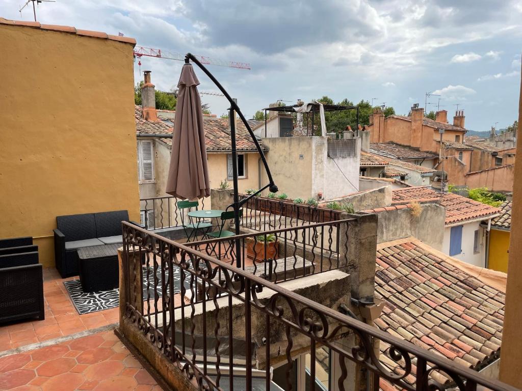 einen Balkon mit einem Sonnenschirm und einem Tisch in der Unterkunft UNE TERRASSE SUR LES TOITS in Aix-en-Provence