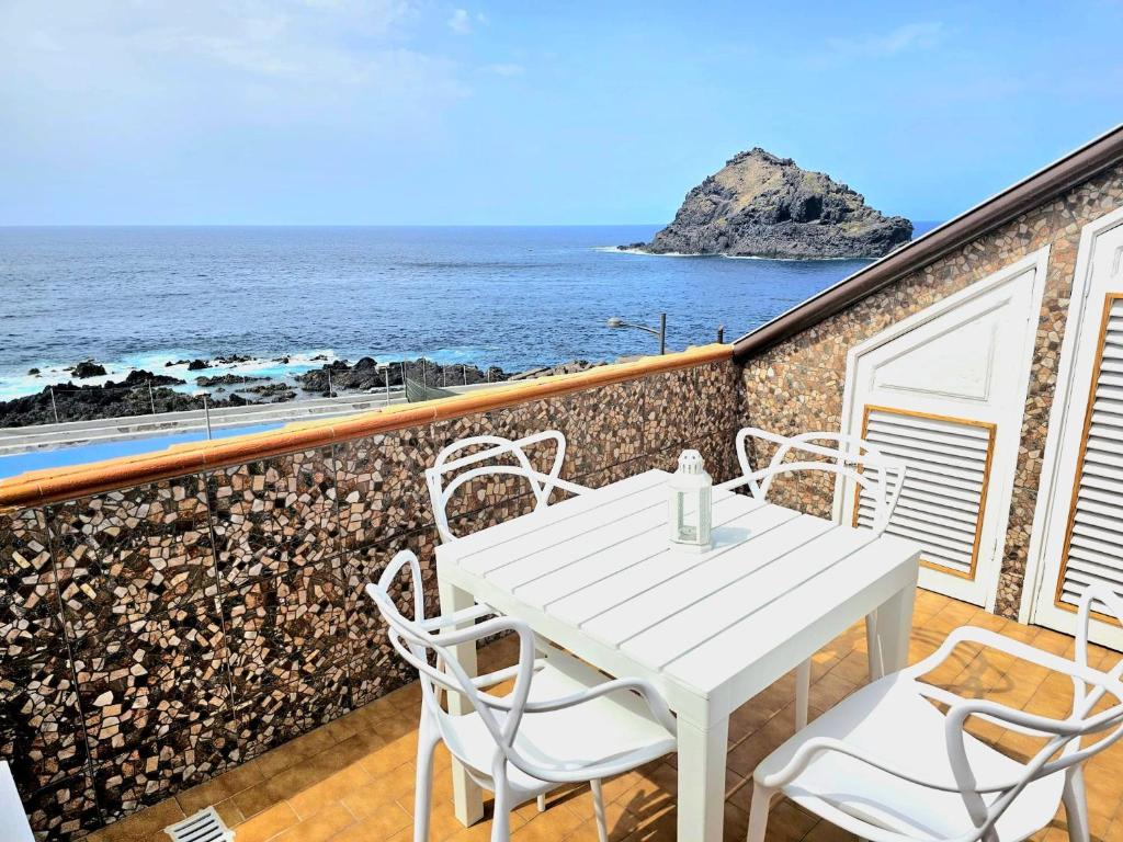 una mesa blanca y sillas en un balcón con vistas al océano en Brisas del Roque Coastline Apartment in Garachico by HRTenerife Net en Garachico