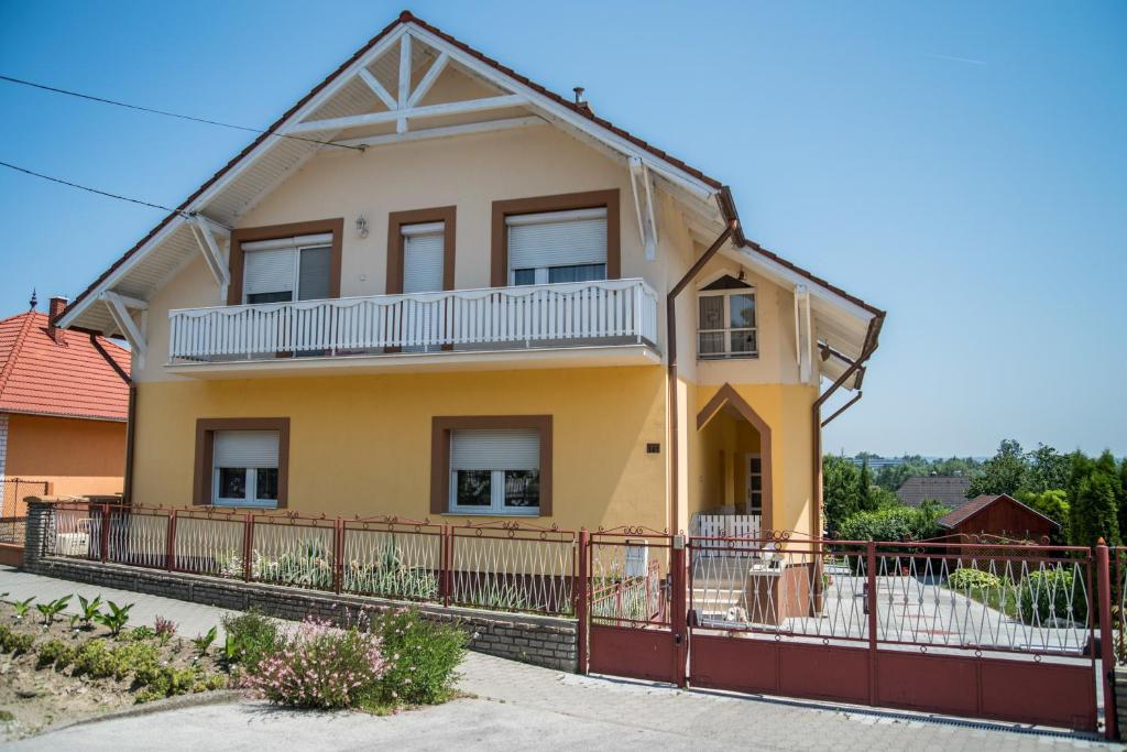 een geel huis met een hek ervoor bij Kámán Vendégház in Alsópáhok