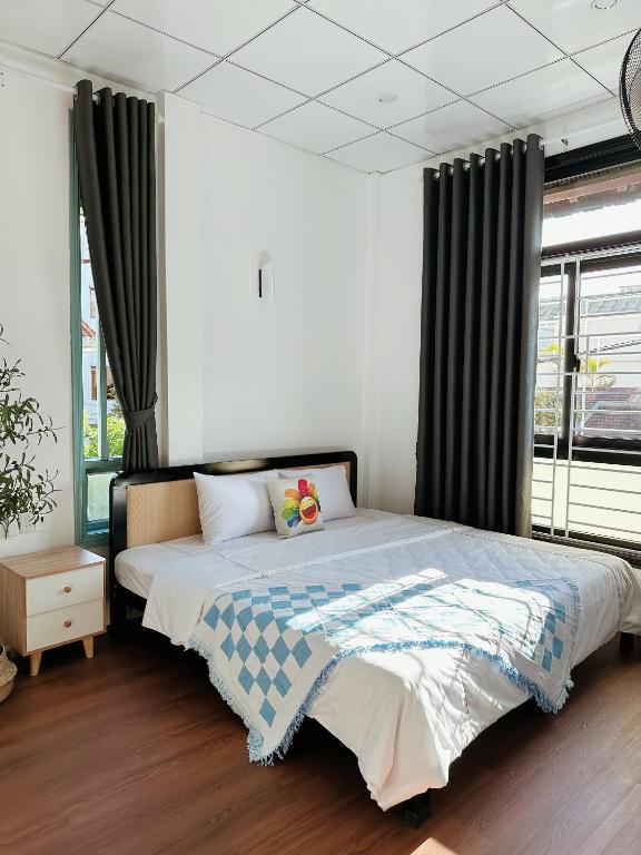 um quarto com uma cama grande e cortinas pretas em Under the Sun Homestay em Hue