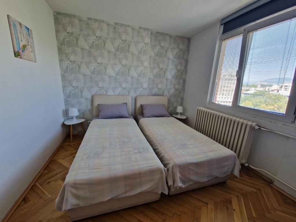 two beds in a small room with two windows at Niko-Max Apartment in Skopje