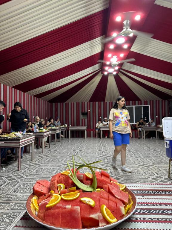 Syndebad desert camp في وادي رم: امرأة تقف في غرفة مع لوحة من البطيخ