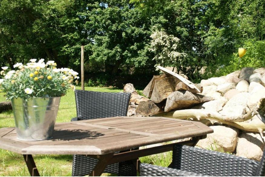 a wooden picnic table with a vase of flowers on it at Ferienwohnung-Auszeit in Hürup