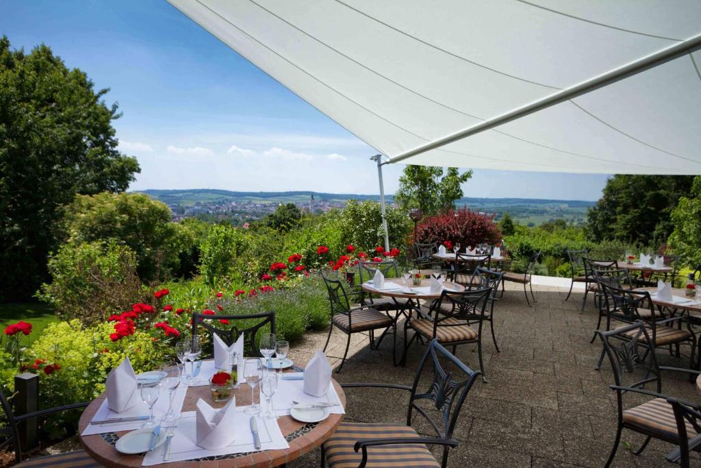 eine Terrasse mit Tischen und Stühlen und Aussicht in der Unterkunft Parkhotel Donauwörth in Donauwörth