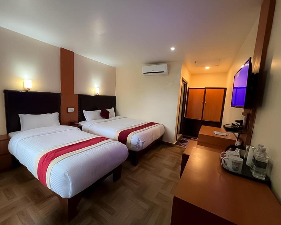 a hotel room with two beds and a flat screen tv at Ama Garden Sauraha in Sauraha
