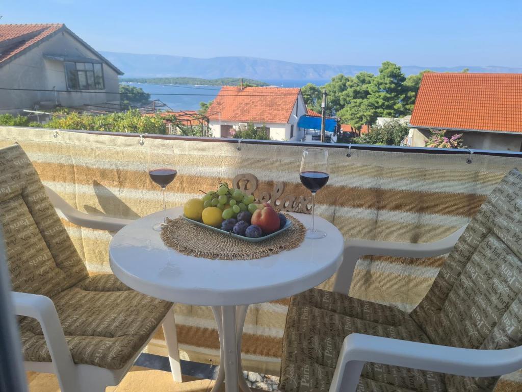 een tafel met een fruitschaal en twee glazen wijn bij Bura in Jelsa