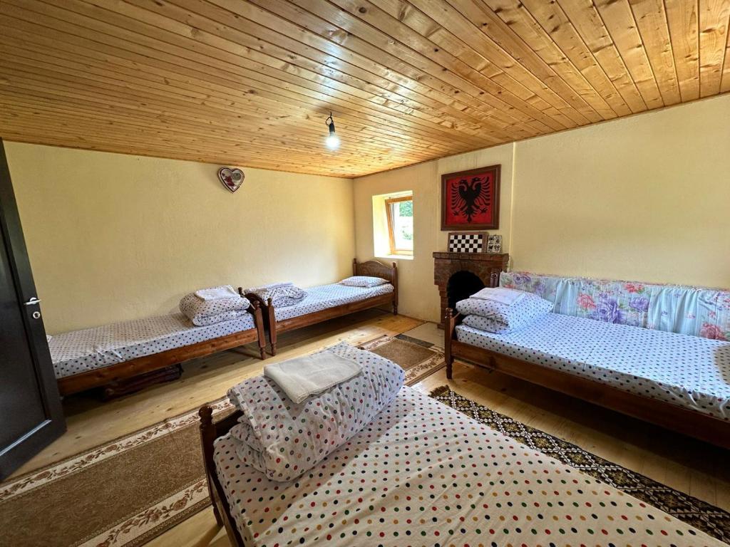 a room with three beds and a wooden ceiling at Guest House Kukaj Valbone in Valbonë