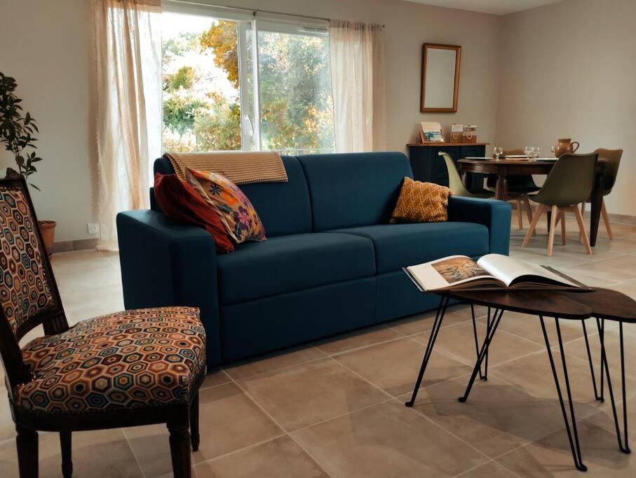 a blue couch in a living room with a table at Charmante maison avec jardin aux portes des gorges de l&#39;Ardèche in Saint-Julien-de-Peyrolas
