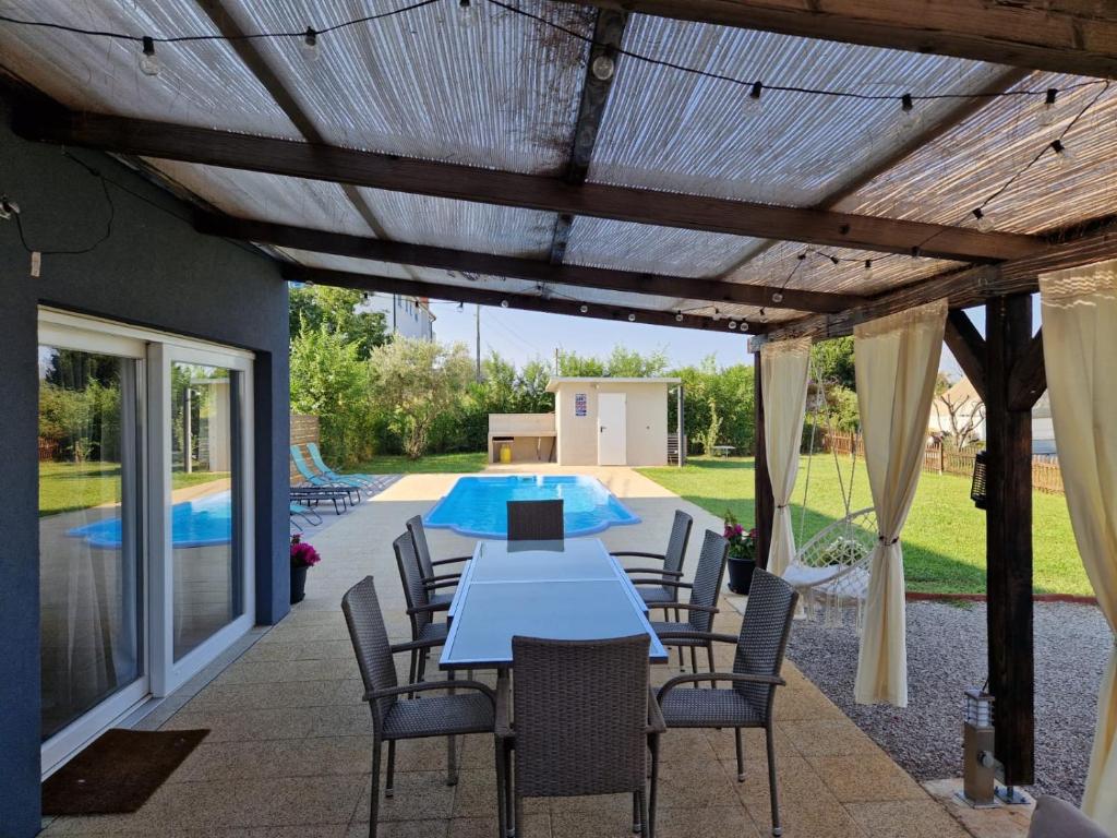 patio ze stołem i krzesłami oraz basenem w obiekcie Villa Makale w mieście Umag