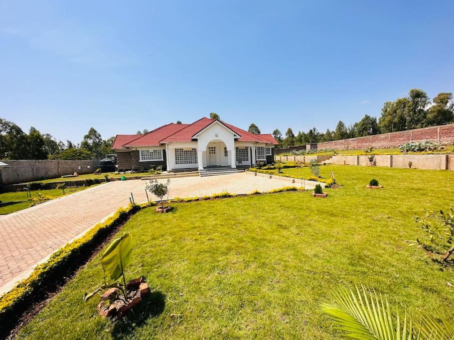 uma casa com um telhado vermelho num jardim verde em R&B Retreat house in Rodi Kopany - Homabay County, Kenya, Africa em Marinde