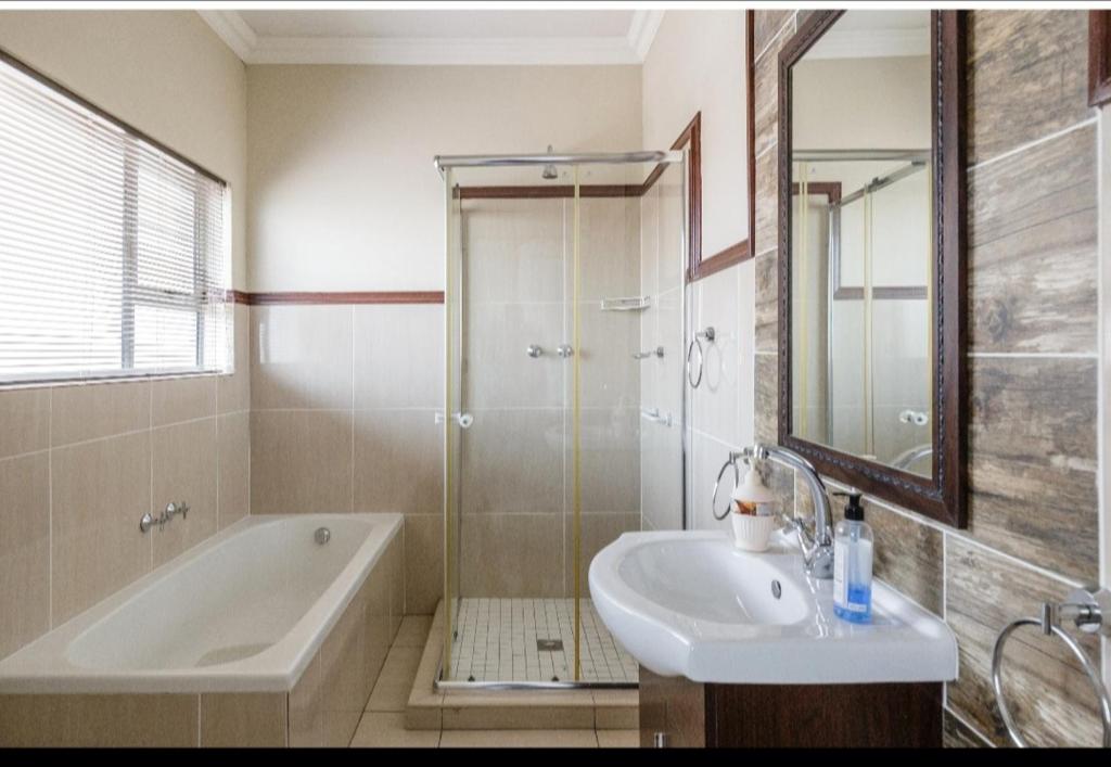 a bathroom with a tub and a sink and a shower at Jewel of Jozi in Edenvale