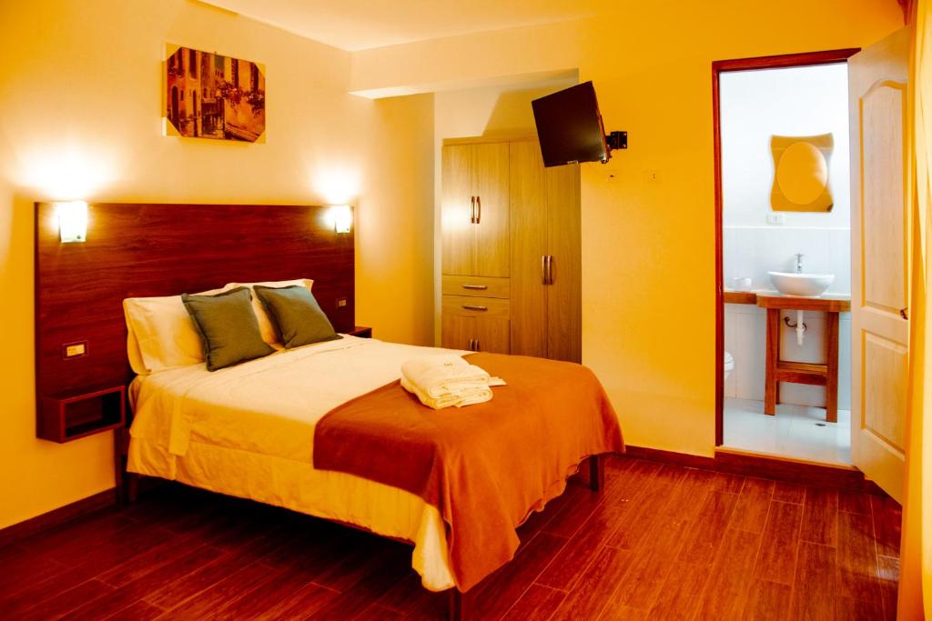 a bedroom with a bed with yellow walls and wooden floors at La Posada D'Benjamín in Oxapampa