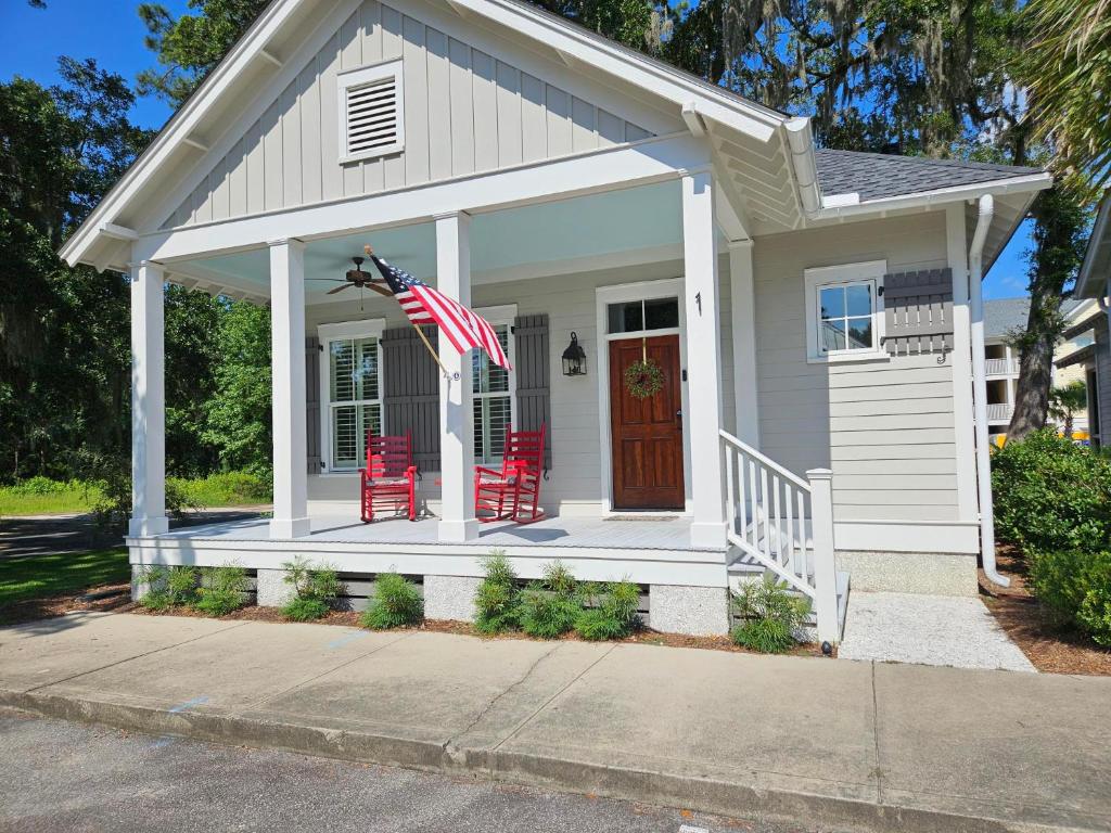a small white house with red chairs and an american flag at Low Country Cottage in Beautiful Habersham in Beaufort