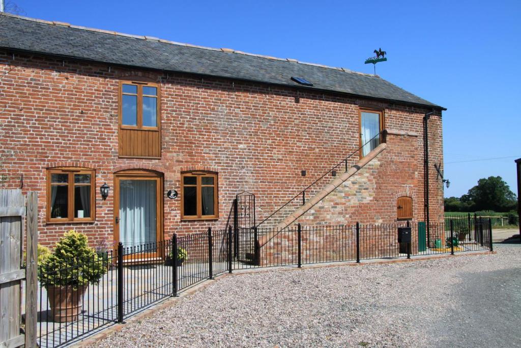 ein Backsteinhaus mit einem Zaun davor in der Unterkunft The Granary Self Catering Cottage in Shrewsbury