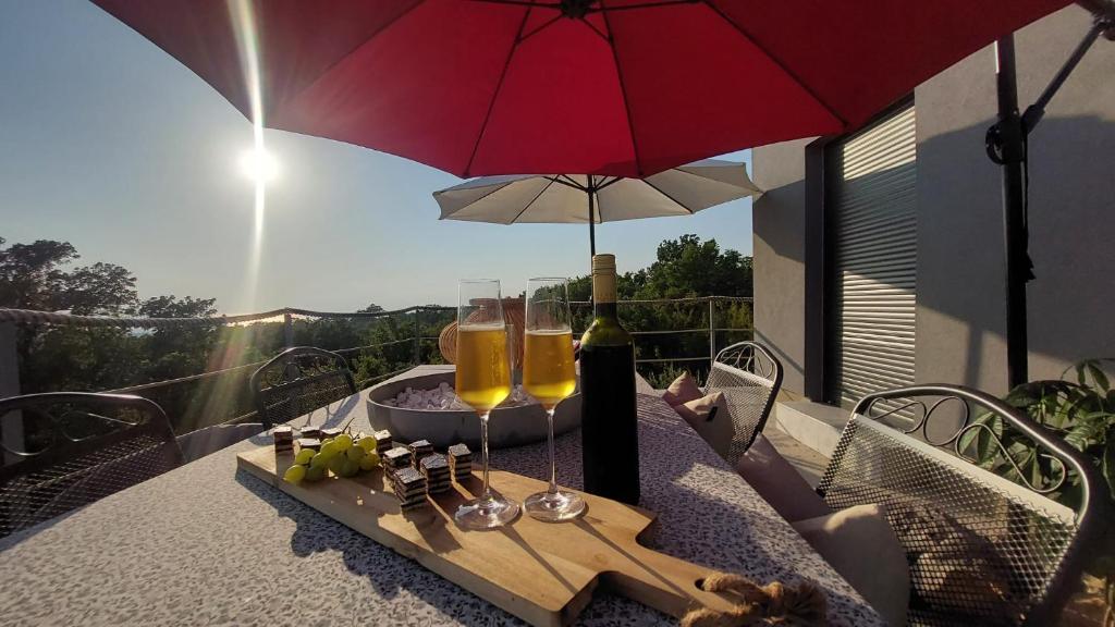 史莫利卡的住宿－Kuća za odmor Eol，一张桌子,上面放着两杯葡萄酒和一把雨伞