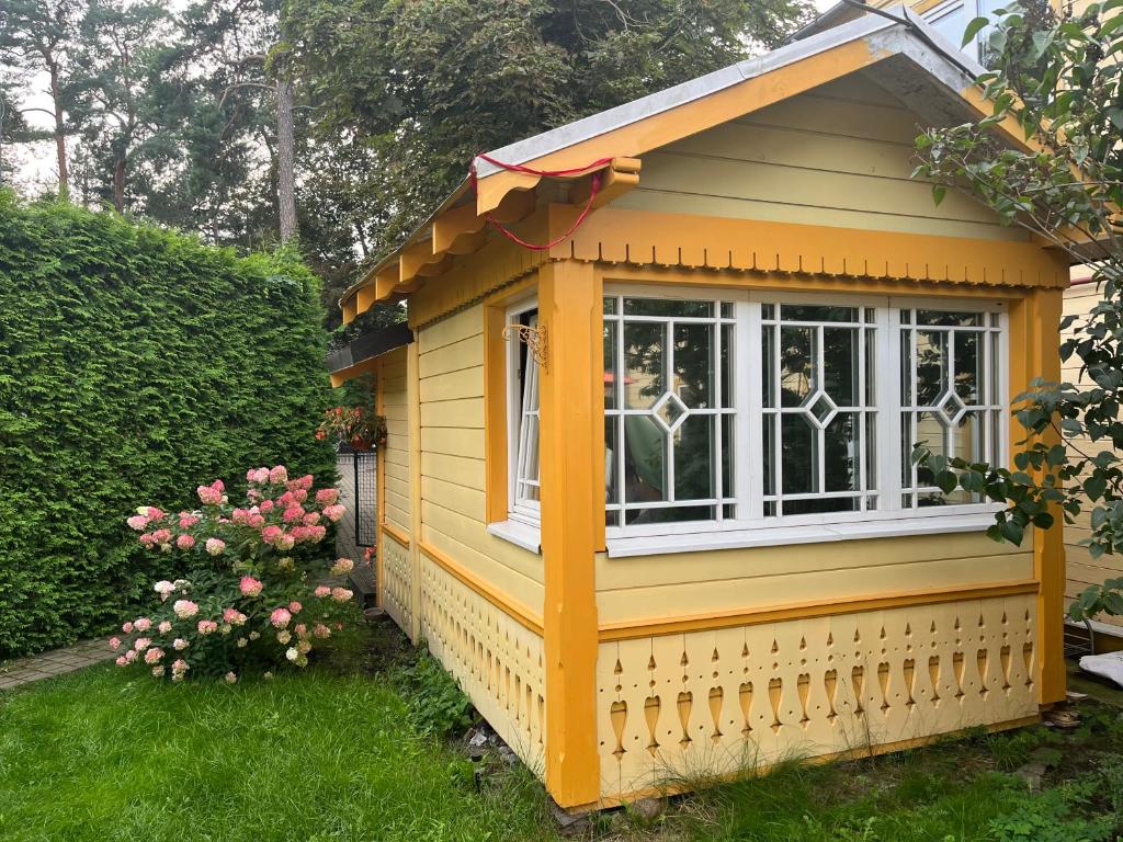 a small yellow house with a window in a yard at Jurmala`s Center Mini House in Jūrmala