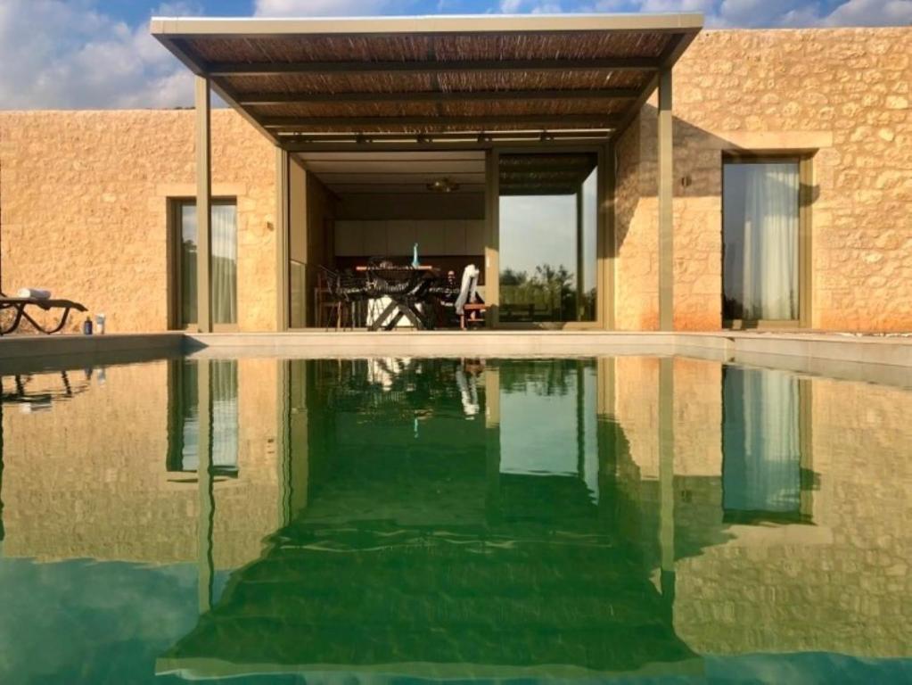 ein Haus mit einem Wasserbecken davor in der Unterkunft Riverstone Villas with private pools in Lévktron