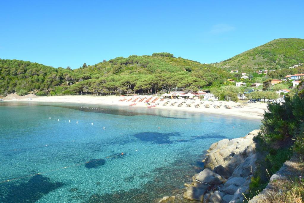 a beach with a bunch of chairs and the ocean at Eco Hotel Montemerlo in Fetovaia