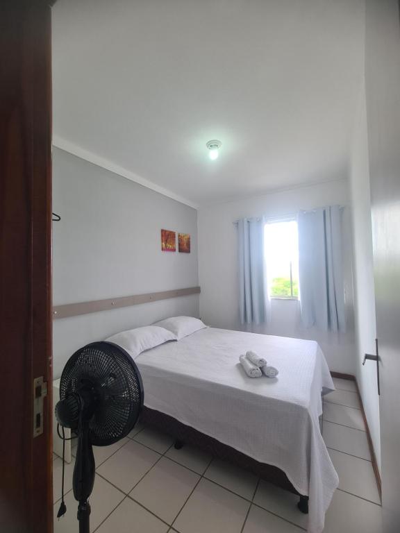 a bedroom with a white bed and a fan at Apartamento aconchegante in Jequié