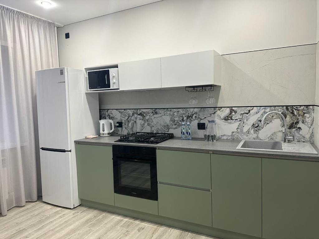 a kitchen with a white refrigerator and a stove top oven at Современная квартира в центре города in Kostanay