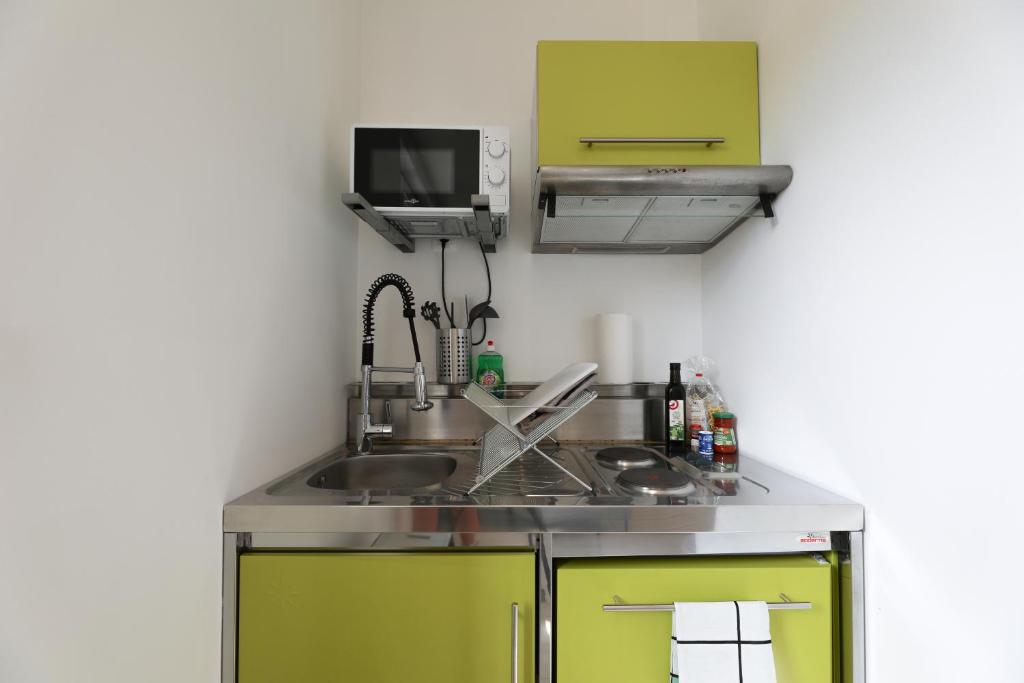 una cocina con armarios verdes y fregadero en Sympathique petit Studio à la frontière du Luxembourg, en Knutange