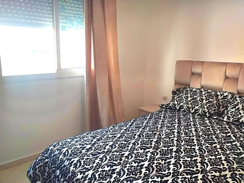 een slaapkamer met een zwart-wit bed en een raam bij Wohnung in martil in Martil