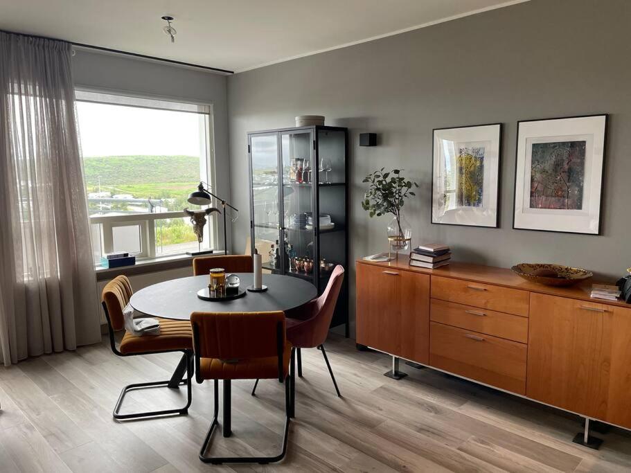 a dining room with a table and chairs and a window at Bright beautiful flat on hilltop w hot tub in Hafnarfjördur