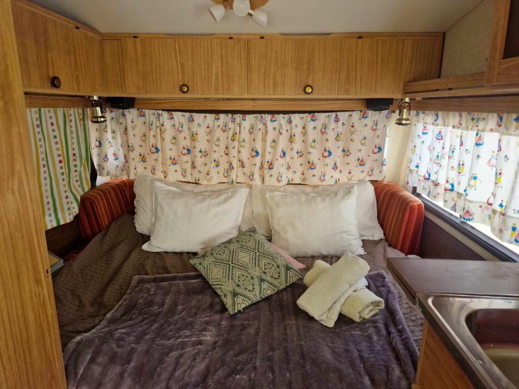 łóżko w przyczepie kempingowej z poduszkami w obiekcie Cozy Caravan With House Access! w mieście Luleå