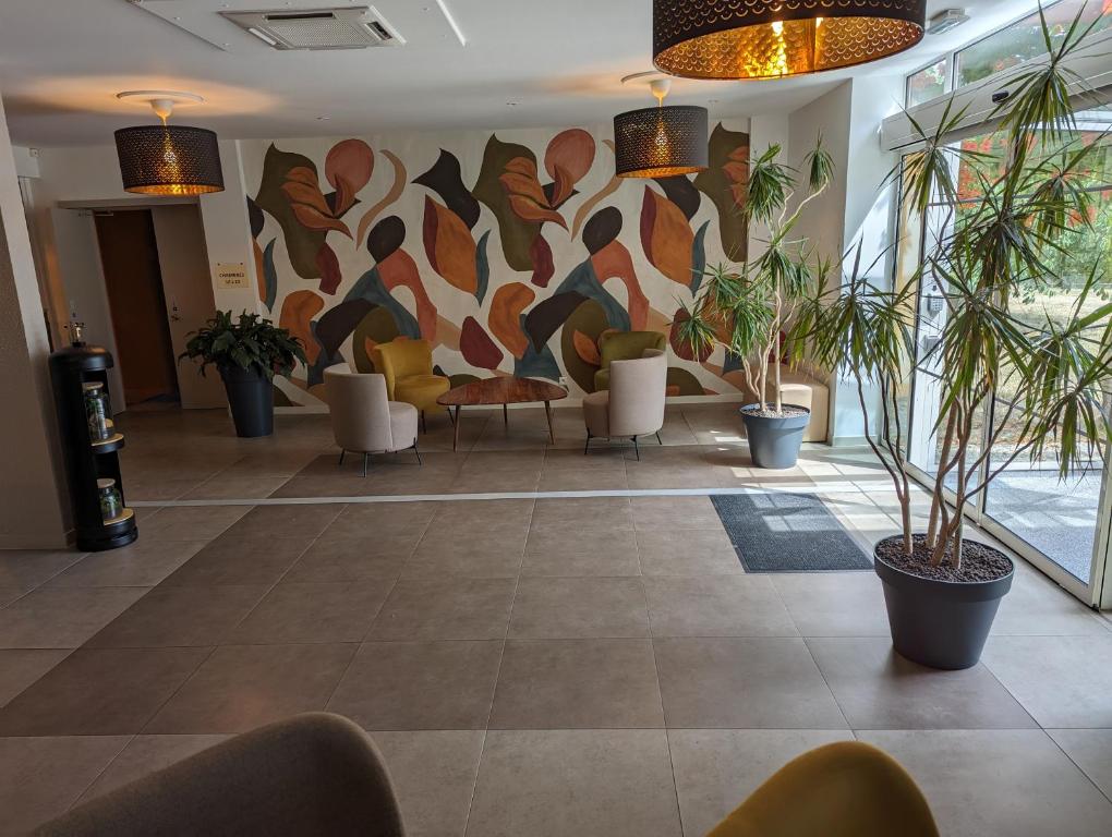 a lobby with potted plants and a painting on the wall at Logis De La Loire in Ancenis