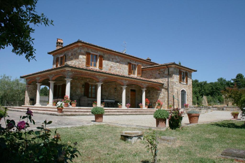 an old stone house with a large yard with flowers at Villa Fosca in Lucignano