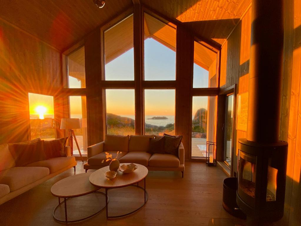 a living room with a fireplace and a couch and a table at Sunset Panorama - Superior Cabin Lofoten in Sand