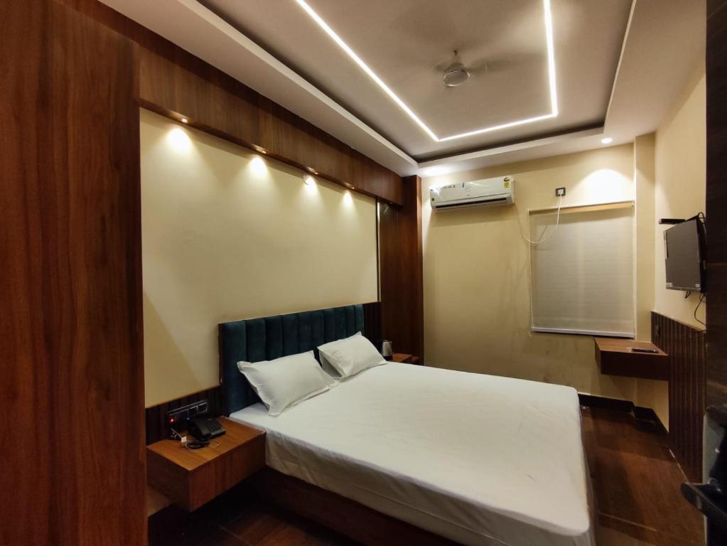 Una pequeña habitación con una cama y un televisor. en HOTEL B S HEIGHTS, en Deoghar